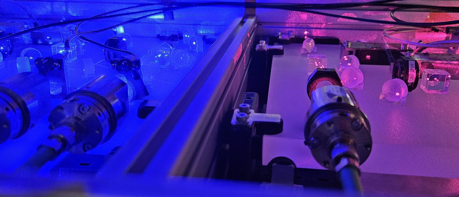 Optical circuit boards of the AQuRA clock lit by blue and red laser light
